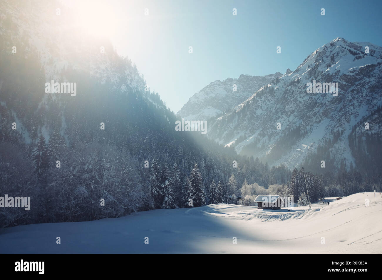 Small Cabin In The Snow Surrounded By Snowy Mountains Stock Photo