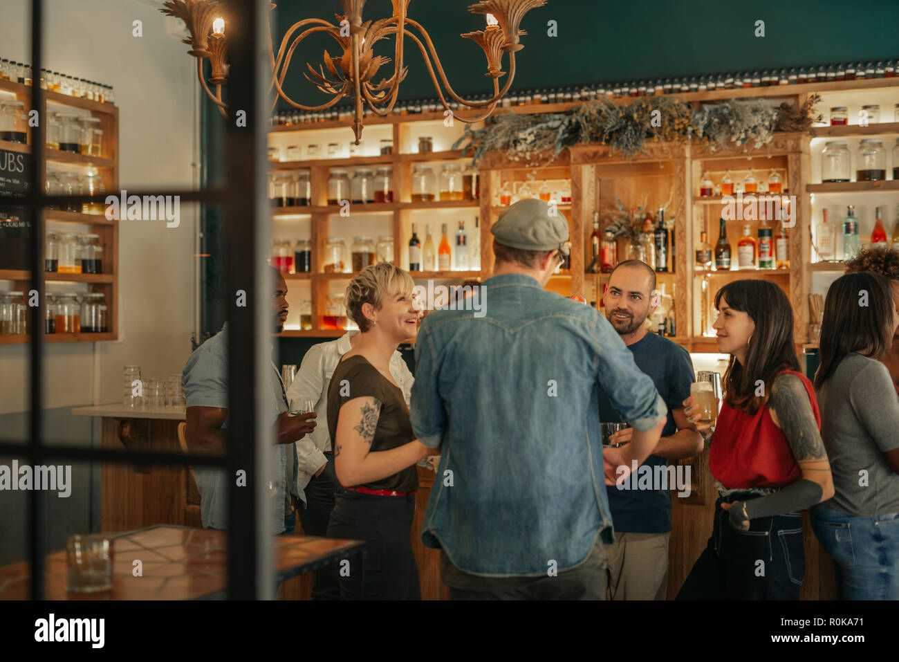 Group of friends standing in a bar having drinks together Stock Photo