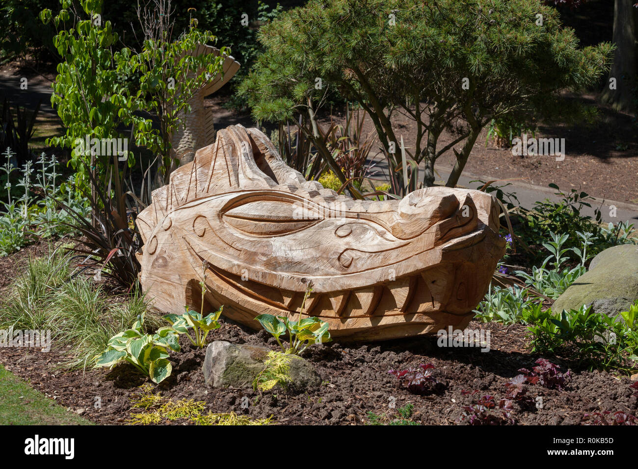A carved wooden dragon head in one of the flower beds at Peasholm Park