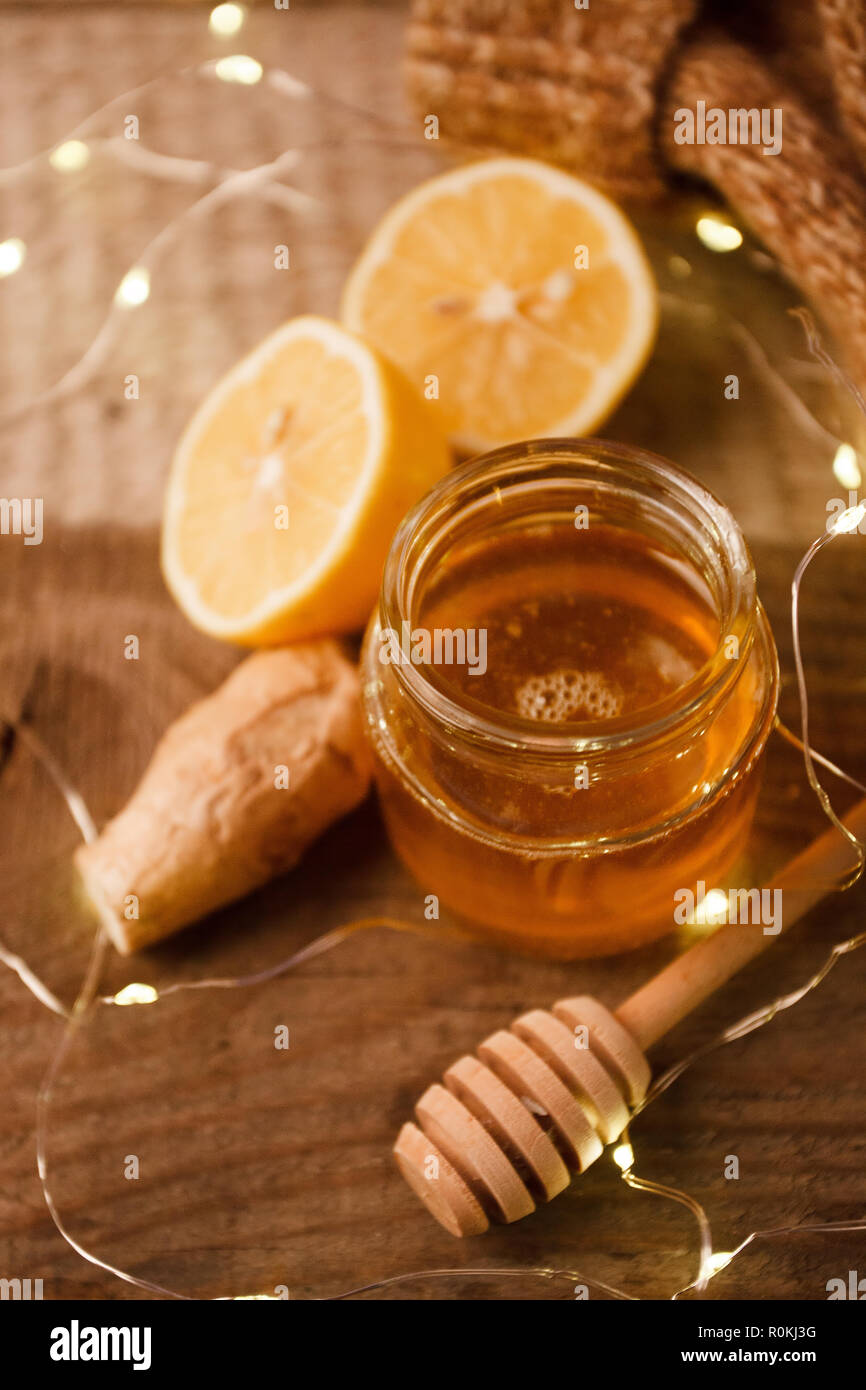 Composition with honey, lemon, ginger root as natural cold remedies on wooden background, winter holiday cozy home concept Stock Photo