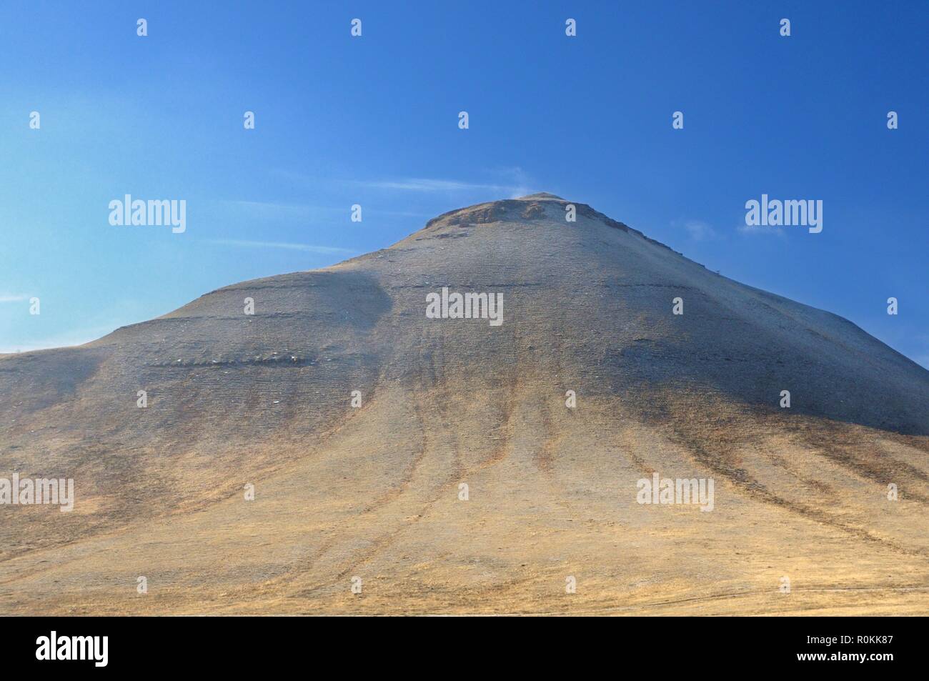 Winter landscape with a hill covered with a yellow dry grass and first snow under dark blue sky in Khakassia Stock Photo