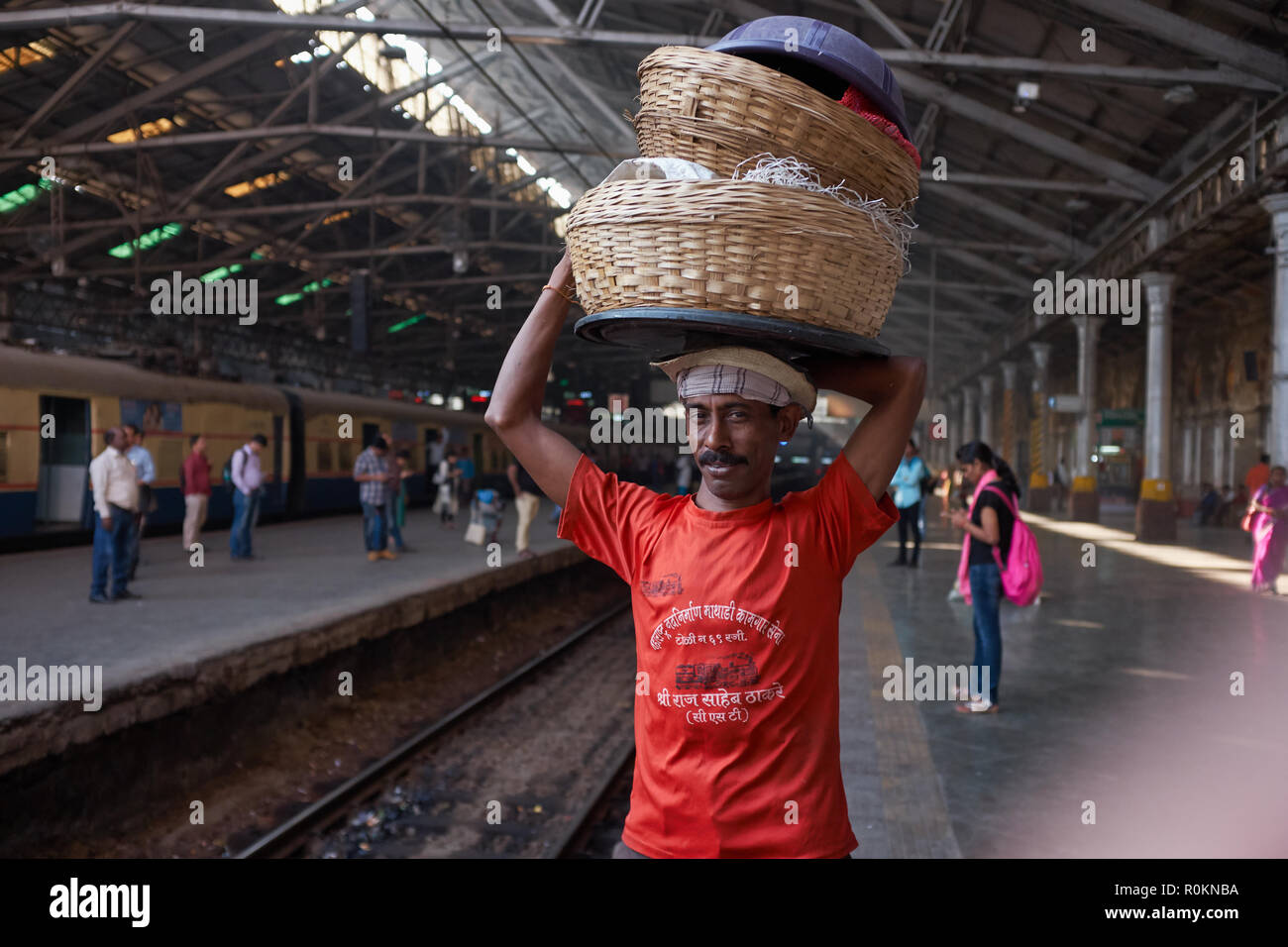A porter at Chhatrapati Shivaji Maharaj Terminus (CSMT) in Mumbai, India, waits for an incoming train to deliver his goods Stock Photo