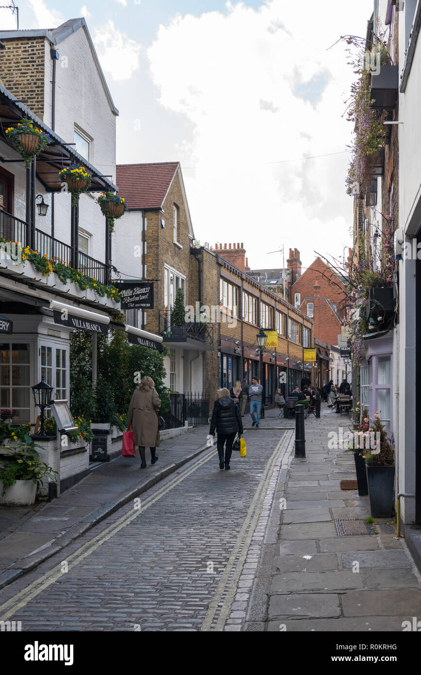 People strolling through Perrin's Court, a pretty narrow street of shops, cafes, and restaurants in Hampstead, London, England, UK Stock Photo