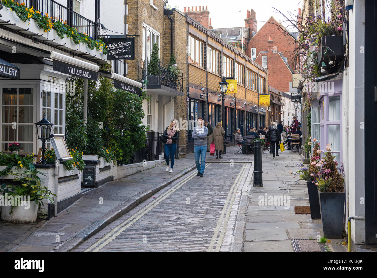 People strolling through Perrin's Court, a pretty narrow street of shops, cafes, and restaurants in Hampstead, London, England, UK Stock Photo