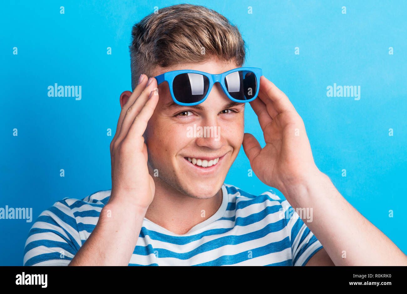 Portrait of a young man holding sunglasses on his forehead in a studio