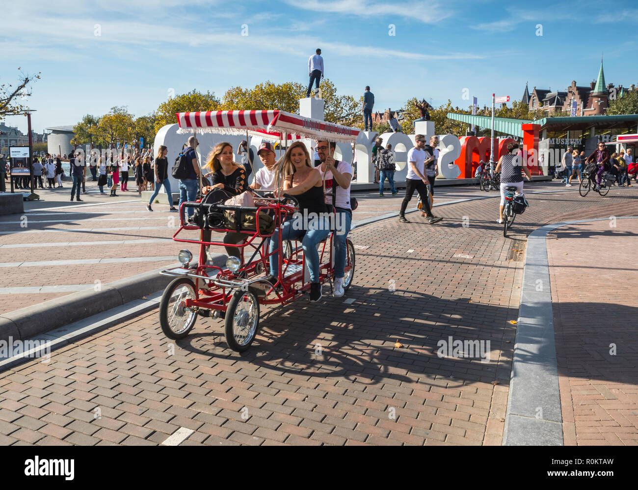 Tourists riding a bicycle carriage near Iamsterdam sign in Museumplein (Museum Square) Stock Photo