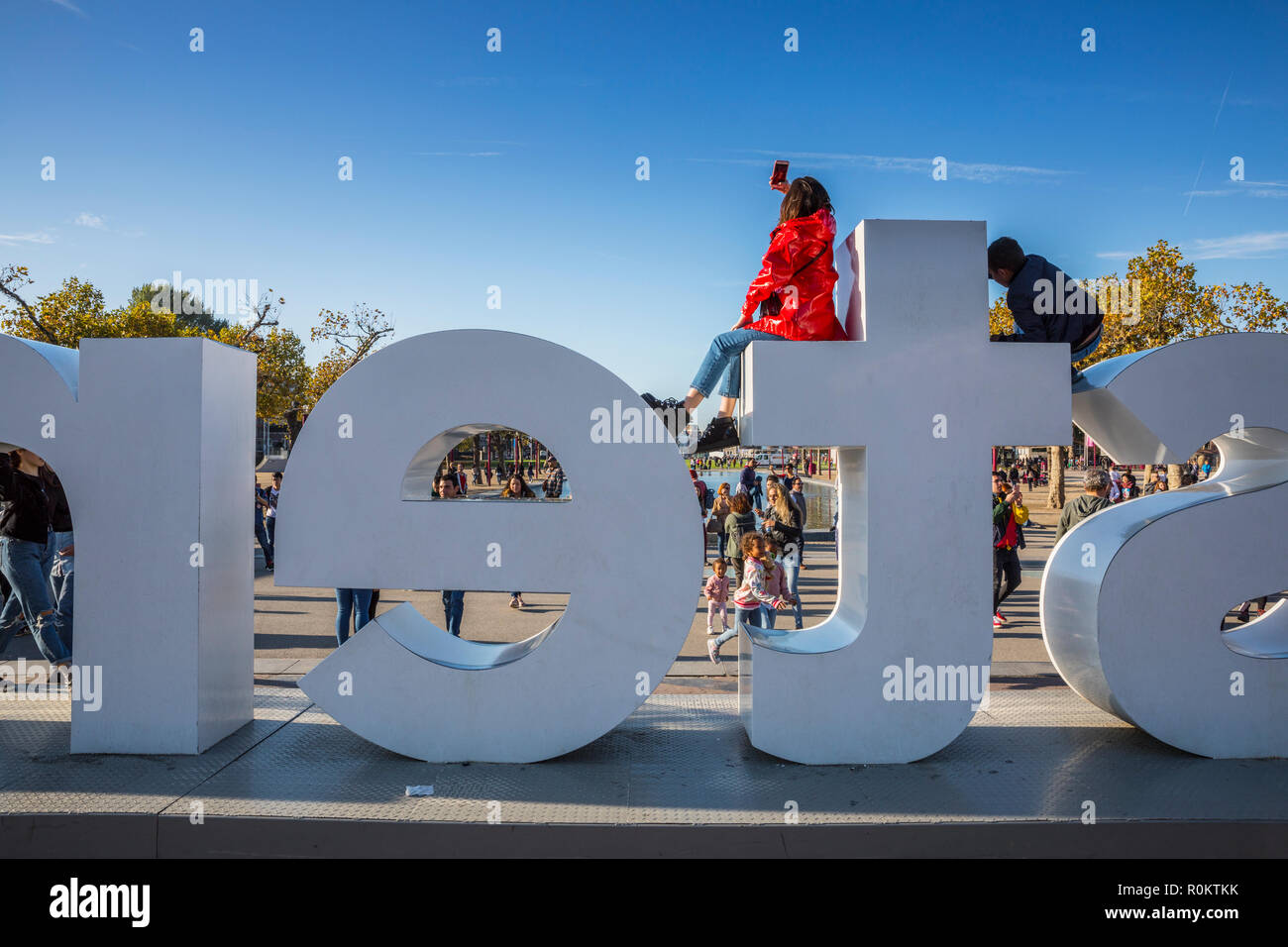 Young woman dressing red jacket making selfi on the top of I amsterdam sign Stock Photo