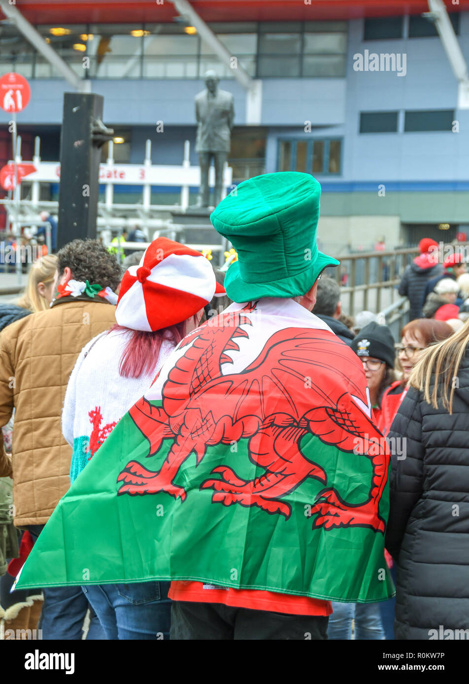 CARDIFF, WALES - NOVEMBER 2018: Person with a green hat and a Welsh flag, the 'Red Dragon', draped over his shoulders in Cardiff city centre on the da Stock Photo