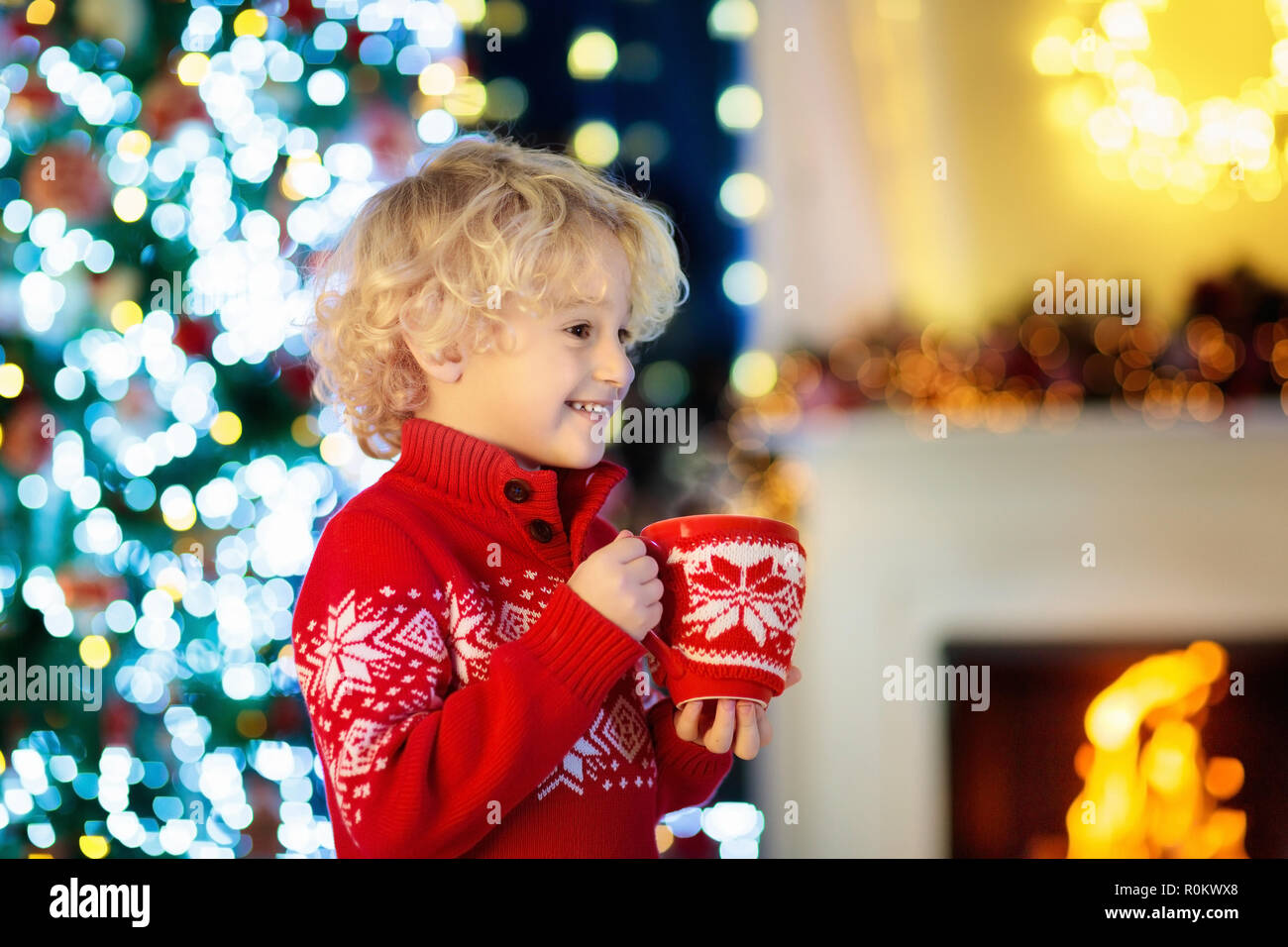 Child drinking hot chocolate at Christmas tree at home. Decorated drink  mug. Little boy in knitted sweater with Xmas ornament holding hot cocoa in  red Stock Photo - Alamy