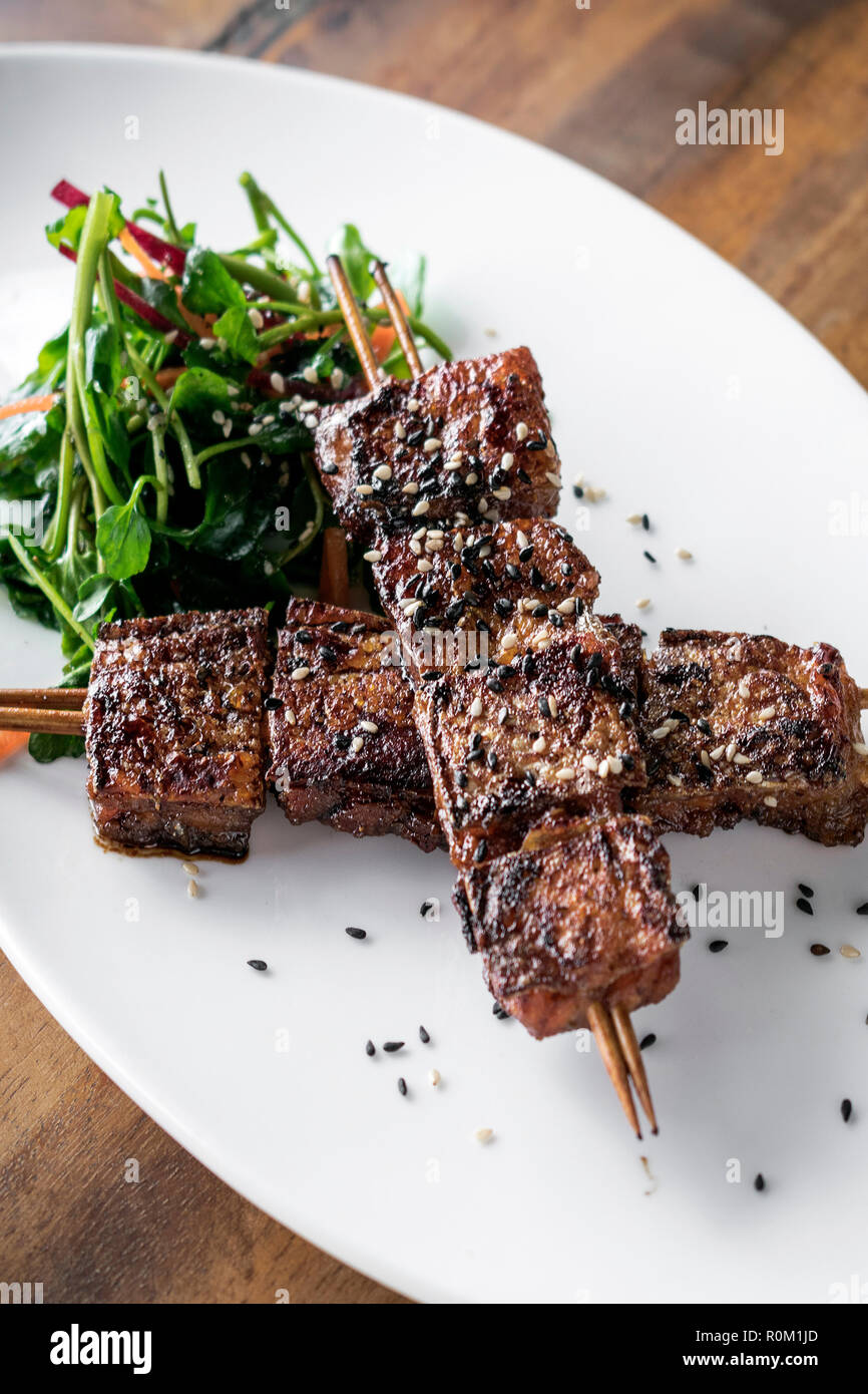 asian spicy sweet soy sauce and sesame seed grilled barbecue pork skewers in singapore restaurant Stock Photo