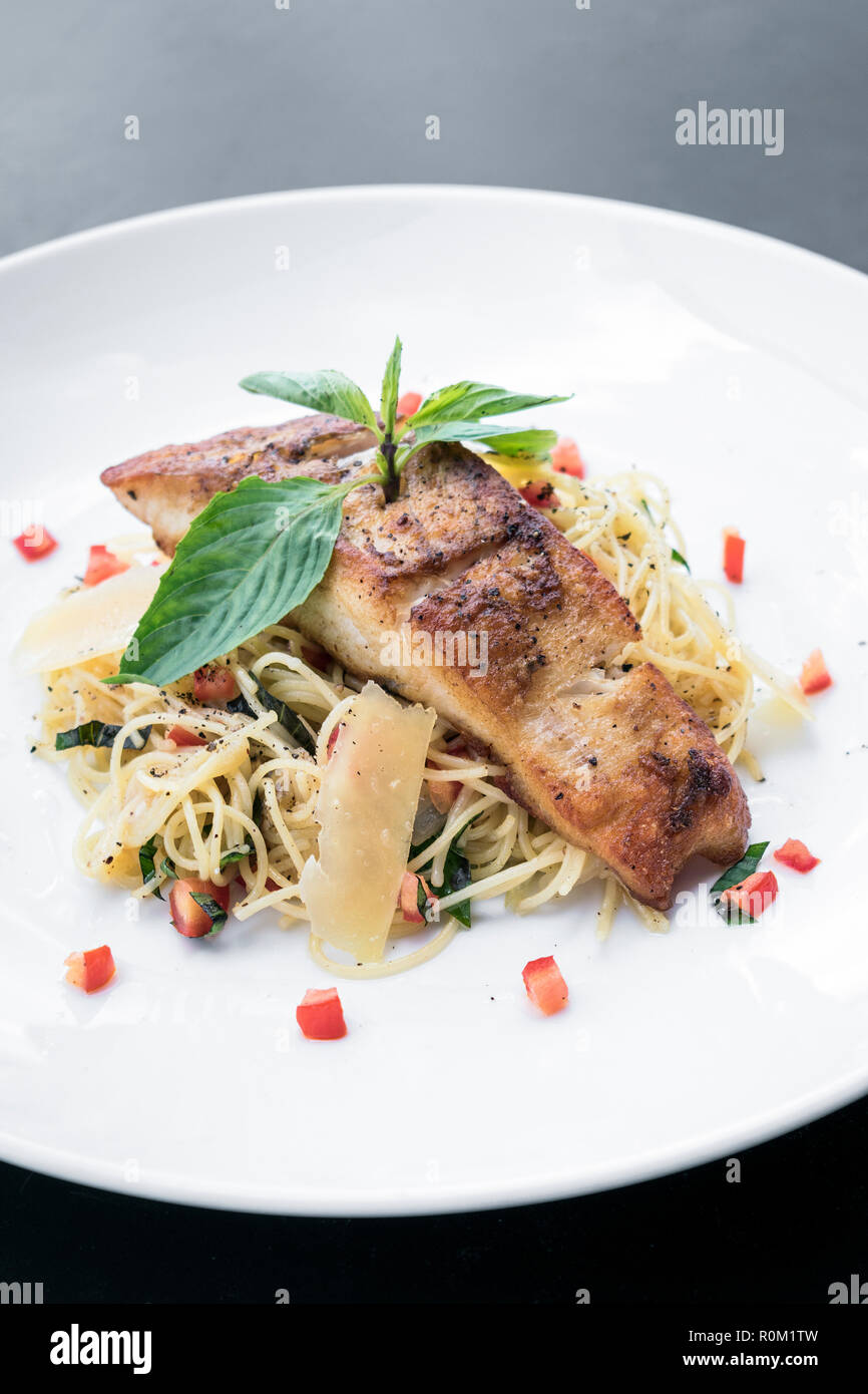 fresh cod fish fillet on mixed vegetable and parmesan spaghetti pasta Stock Photo