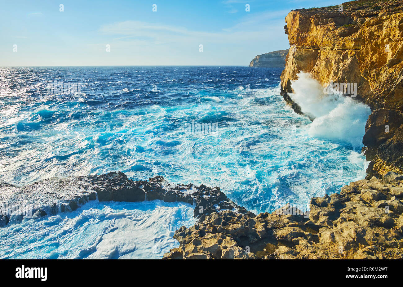 The tall cliffs at the former Azure Window site are best place to watch the storm, the strong foamy waves crash against the rocks with roar, San Lawre Stock Photo