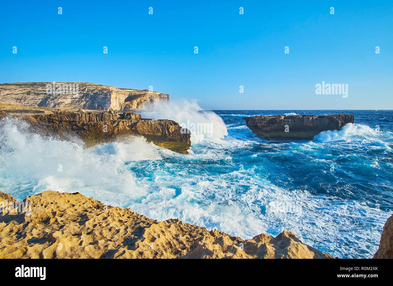 Indented rocky Dwejra coast is perfect place to watch the storm with massive foamy waves, meeting the coast with roar, San Lawrenz, Gozo, Malta. Stock Photo