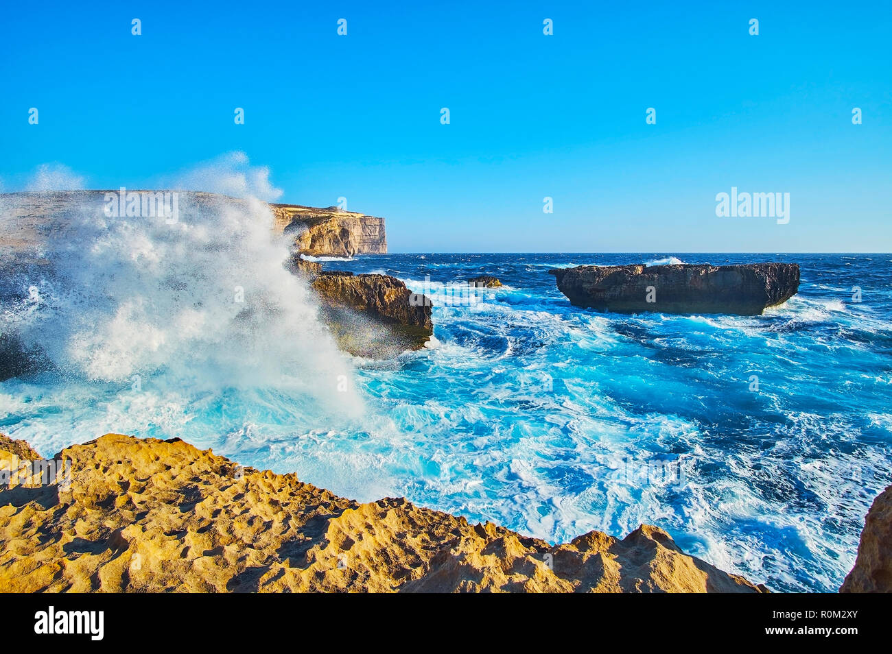 The stormy waves with white splashes cover the rocky coast of San Lawrenz, neighboring with Azure Window (Dwejra) site, Gozo, Malta. Stock Photo