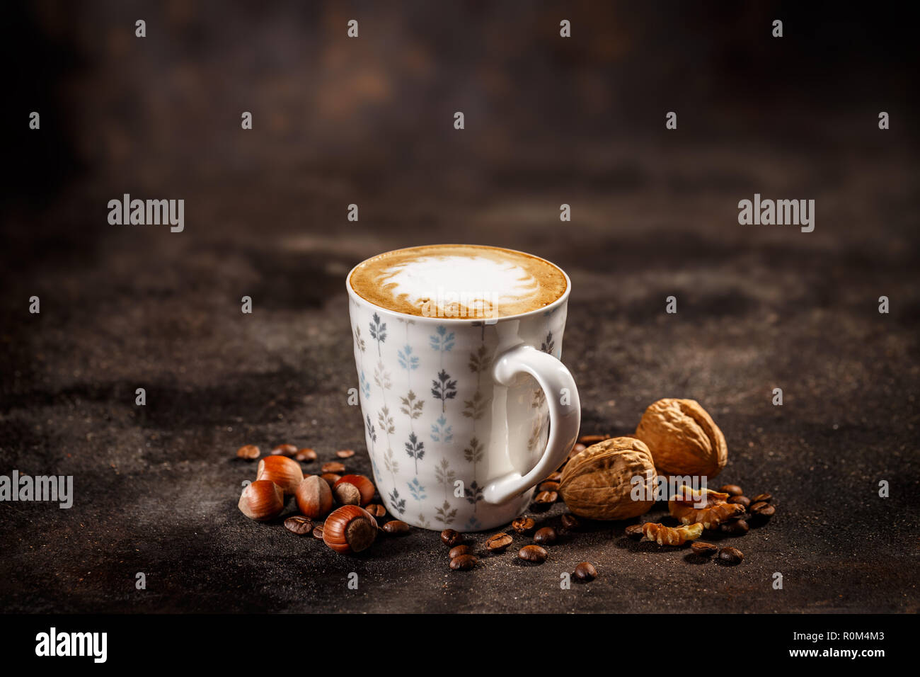 Mug of coffee latte with hazelnut and walnut flavour on a vintage dark background Stock Photo
