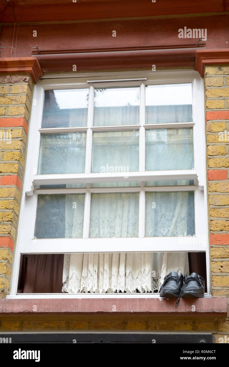 Pair of mens shoes drying on window sill with open sash window Stock Photo