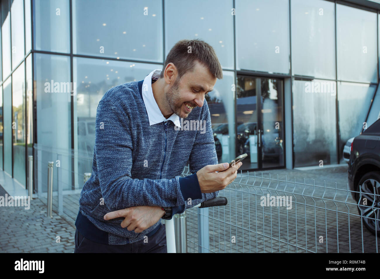 Young man holding coffee and smartphone posing at street and smiling Stock Photo