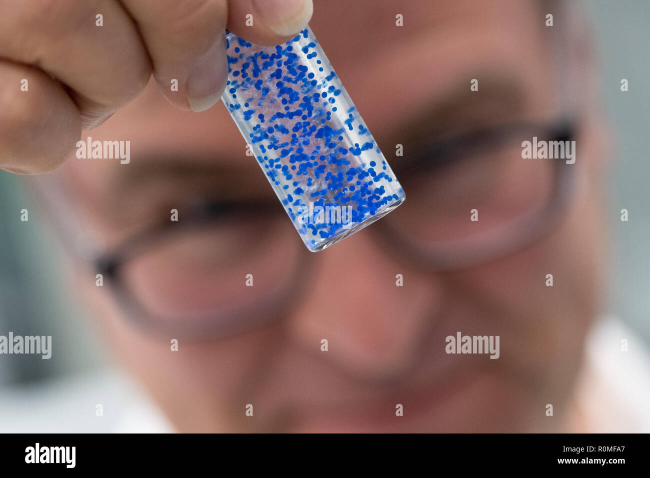 Holzminden, Germany. 23rd Oct, 2018. Ralf Bertram, an employee of Symrise AG, holds a plastic bottle with 'ActiPearls' at the encapsulation system. Symrise is one of the world's leading suppliers of fragrances and flavors. Credit: Swen Pförtner/dpa/Alamy Live News Stock Photo