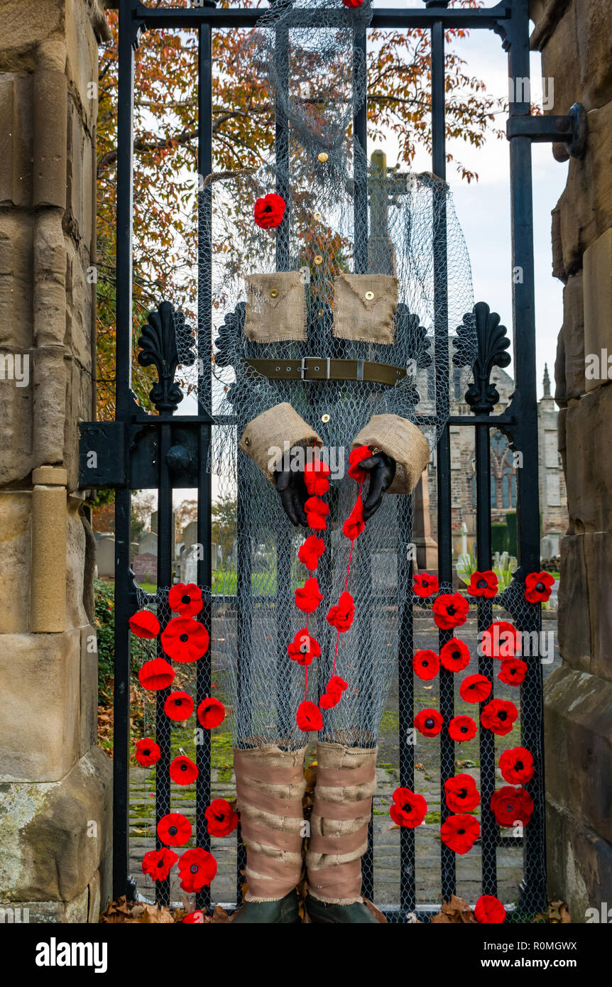 Haddington, East Lothian, Scotland, United Kingdom, 6th November. UK Weather: Sunshine at St Marys' Parish Church where a handcrafted soldier made from chicken wire mesh decorated with poppies stands guard at the gate Stock Photo