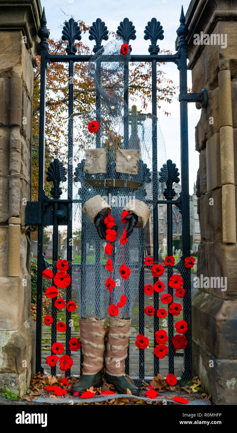 Haddington, East Lothian, Scotland, United Kingdom, 6th November. UK Weather: Sunshine at St Marys' Parish Church where a handcrafted soldier made from chicken wire mesh decorated with poppies stands guard at the gate Stock Photo