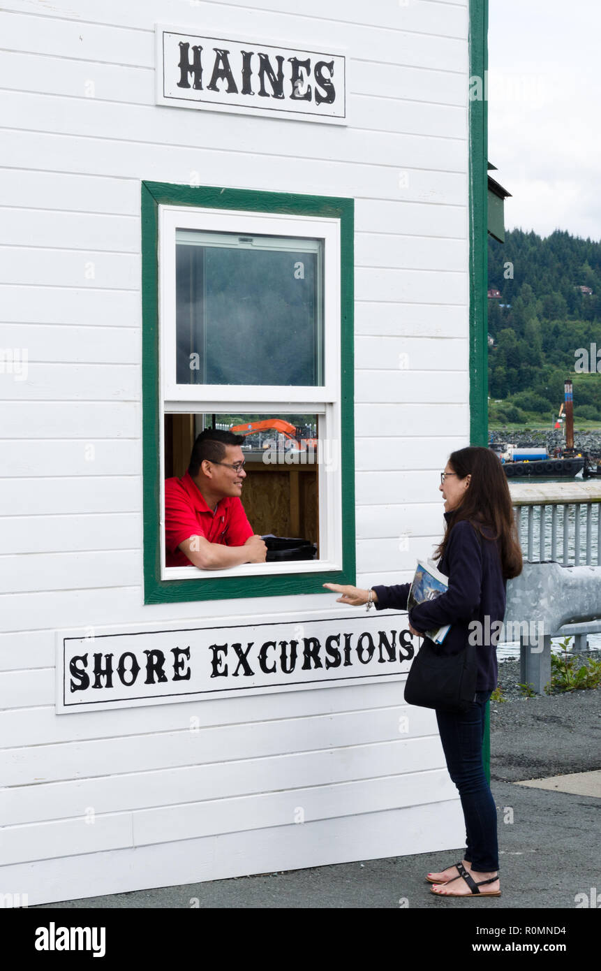 Tourist from cruise ship speaks with tourist agent at shore excursions hut -   Haines, Alaska, United States Stock Photo