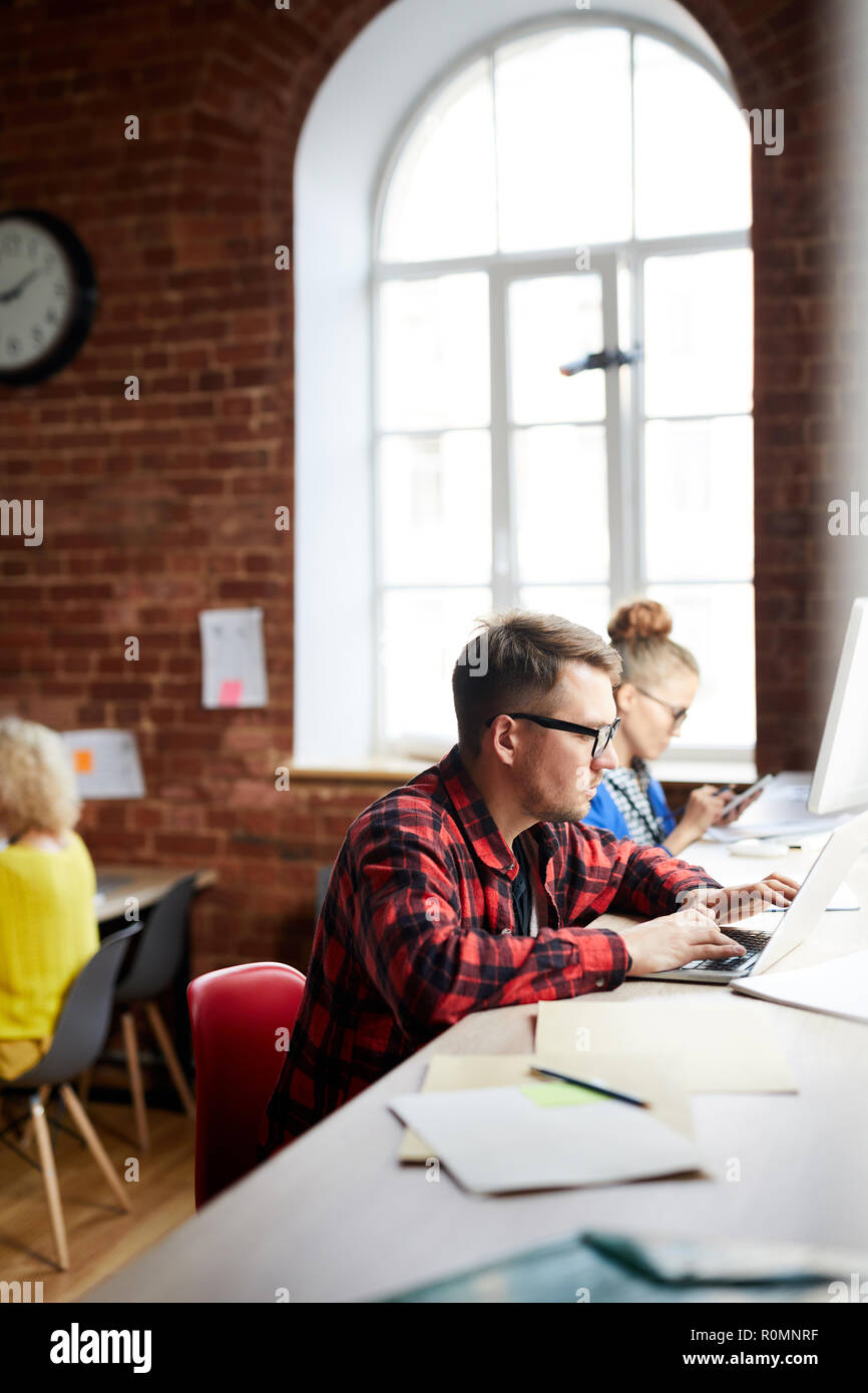 Some managers co-working while sitting by table and using modern gadgets Stock Photo
