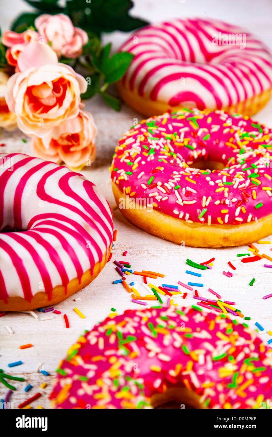 Pink donuts and rose on a wooden background. Delicious dessert. Stock Photo
