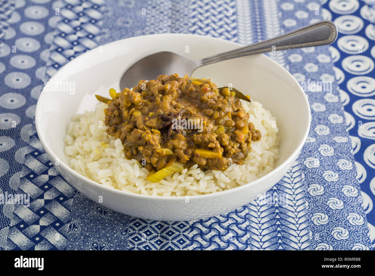 Lentil vegetable curry and rice close up on indigo ethnic printed blue and white tablecloth background Stock Photo