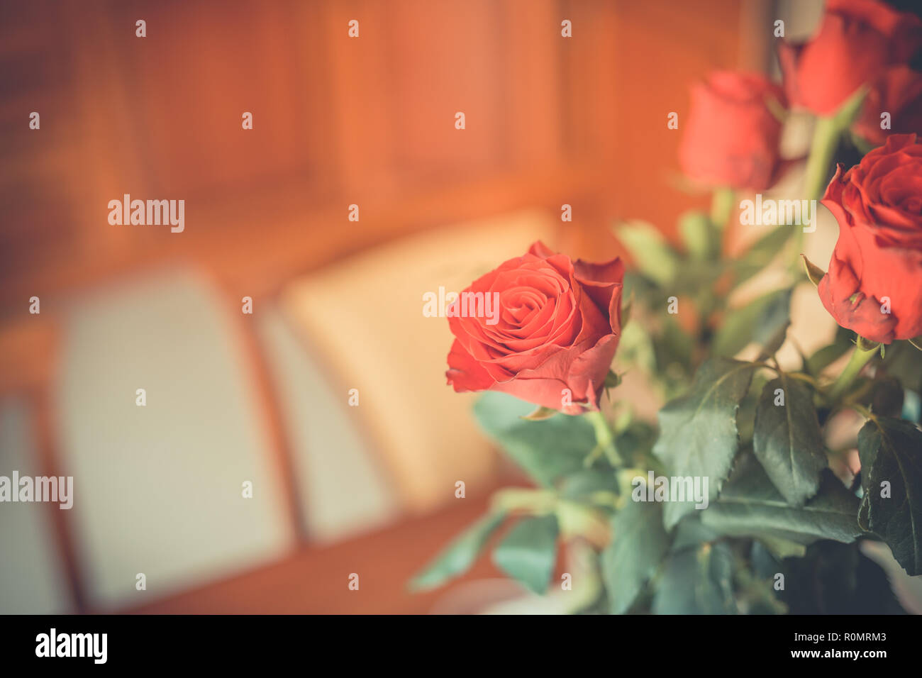 Vase with the red roses standing on the table. Celebrating life event, birthday, valentines day. Romantic cozy home detail, man buy flowers for woman Stock Photo