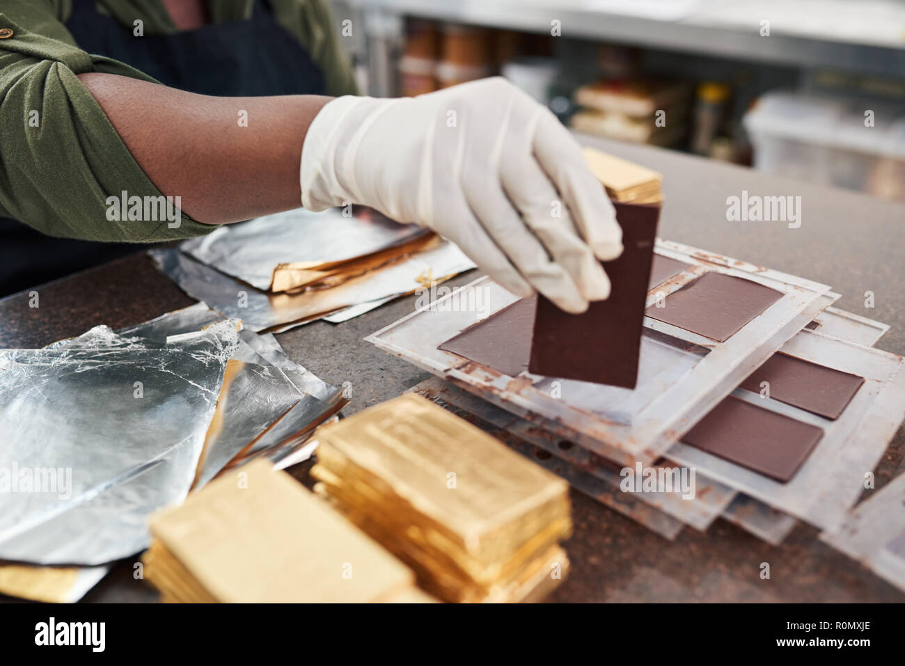 Worker wrapping chocolate bars from molds in gold foil Stock Photo Alamy
