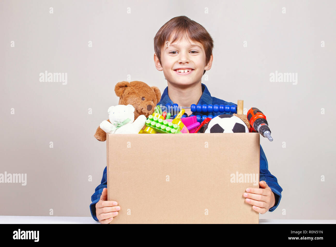 Donation concept. Kid holding donate box with clothes, books, school