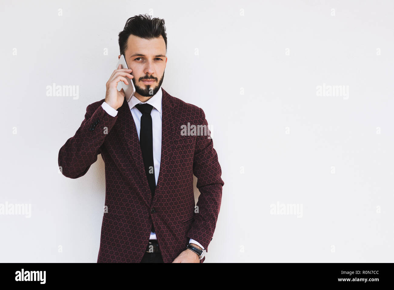 Trendy and fashionable businessman posing on a white background and talking on the phone. Stock Photo