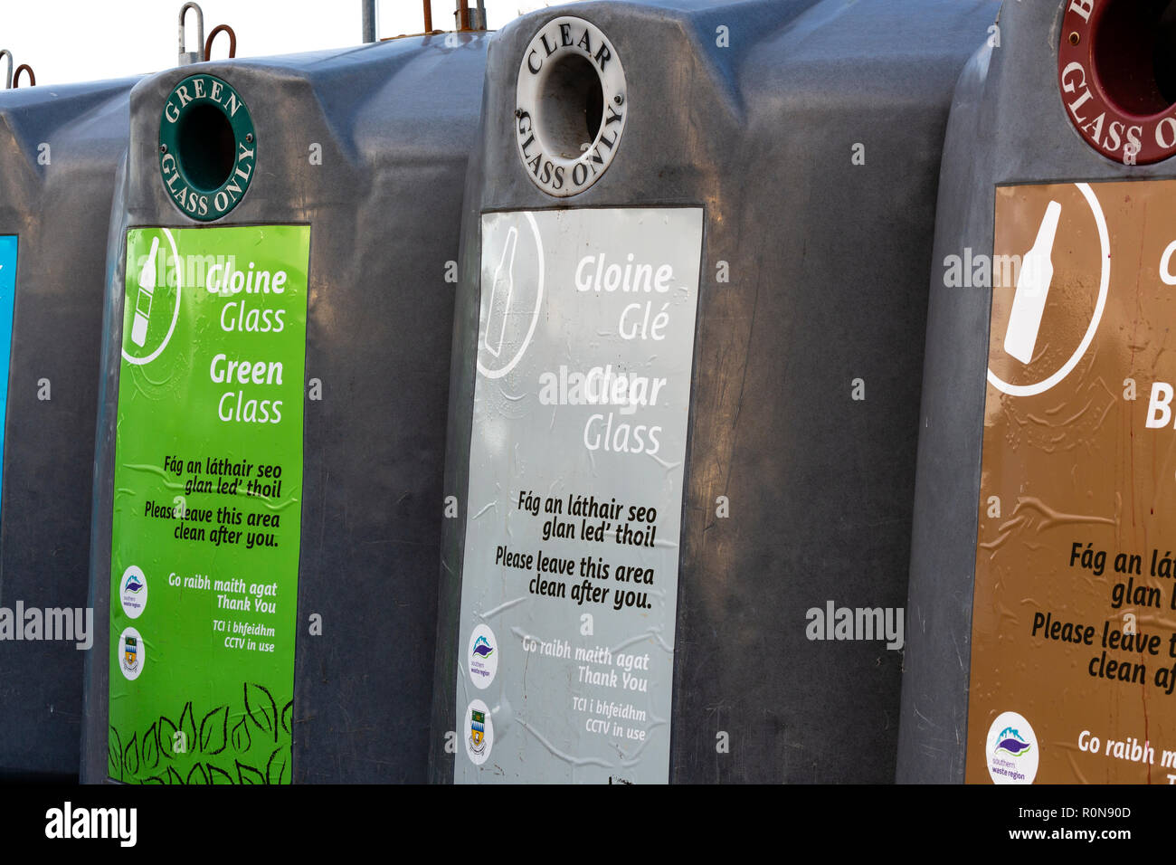 Glass recycling bins for various colours with Irish writing Stock Photo Alamy