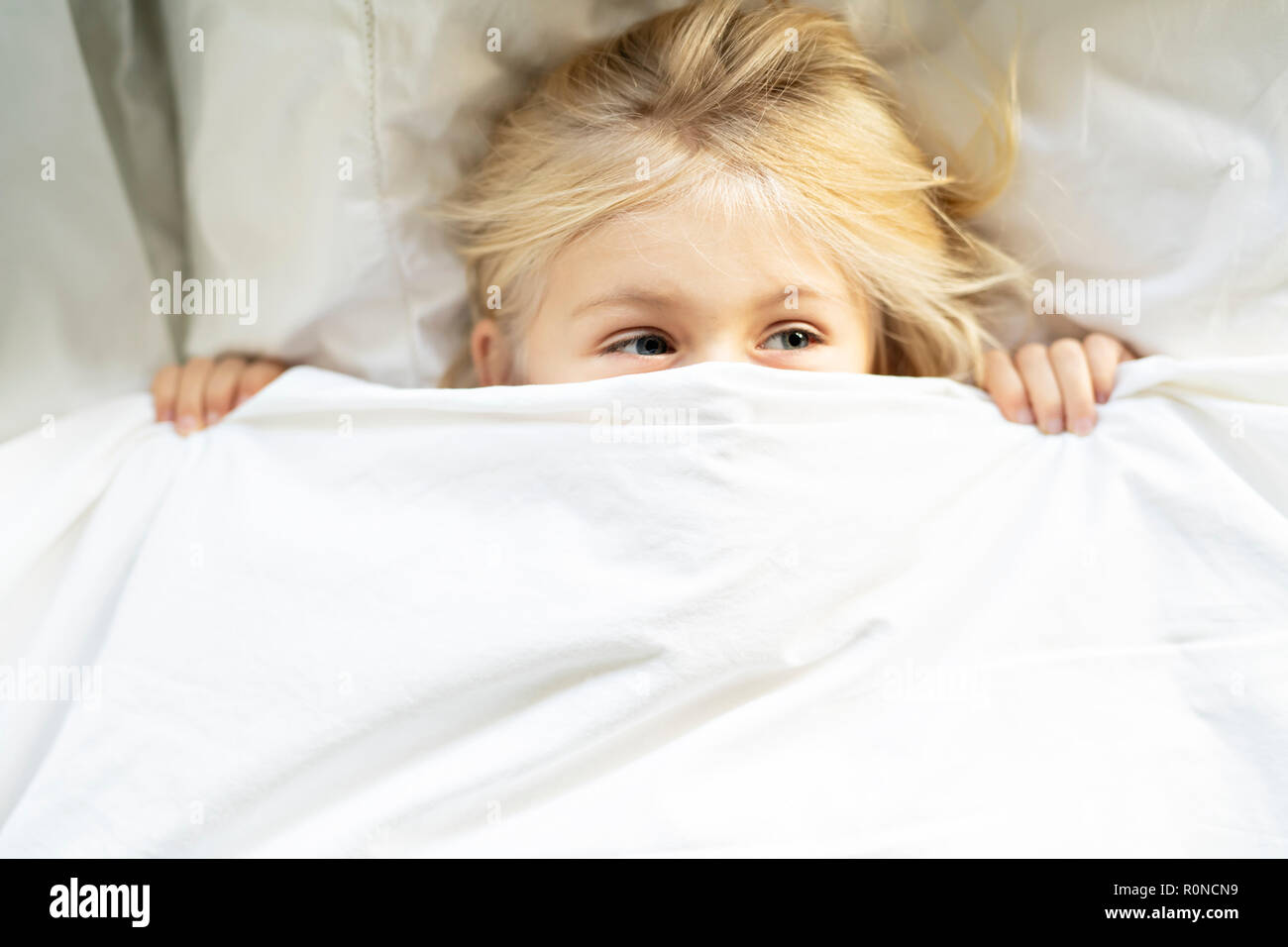 A little girl in bed below the covers Stock Photo Alamy