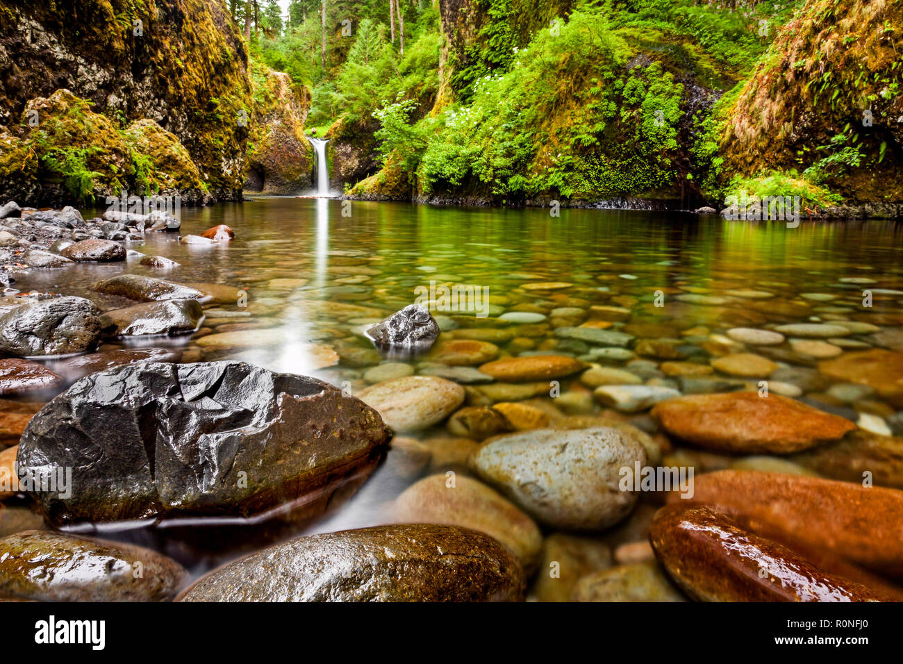 Punch Bowl Falls along the Eagle Creek Trail in Oregon with focus on the rocks in the foreground Stock Photo