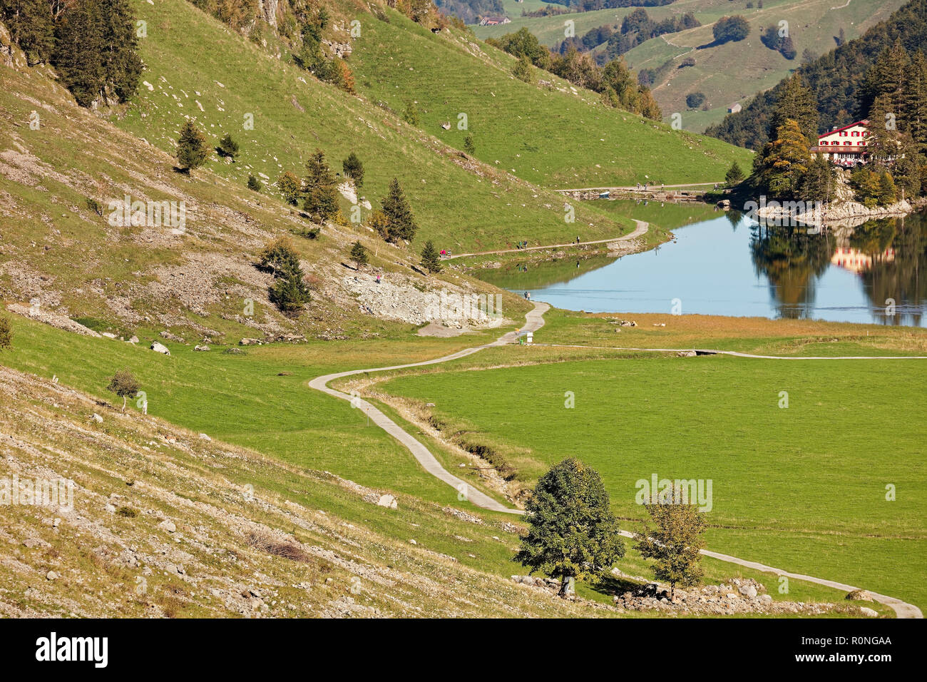Sunny views of pastures, Seealpsee Inn, Forelle Inn from Oberstofel by Seealpsee lake in Alpstein, Appenzell Alps, Switzerland Stock Photo
