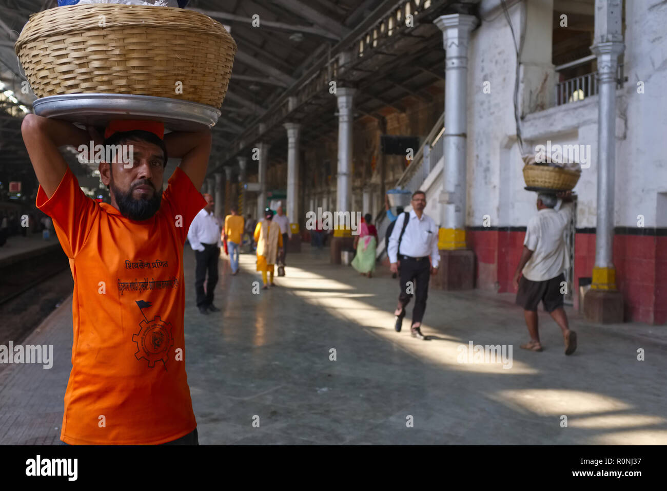 A porter at Chhatrapati Shivaji Maharaj Terminus (CSMT) in Mumbai, India, waits for an incoming train to deliver his goods Stock Photo
