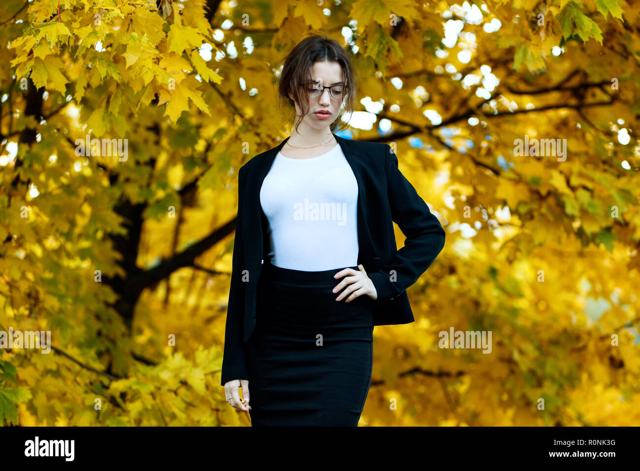 Business woman in formal wear stands over yellow autumn trees. Stock Photo