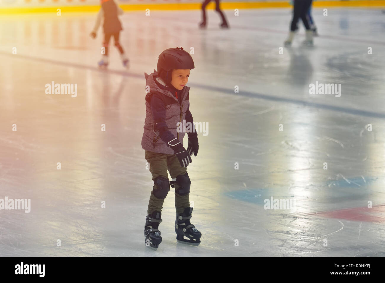 Adorable little boy in winter clothes with protections skating on ice rink Stock Photo Alamy