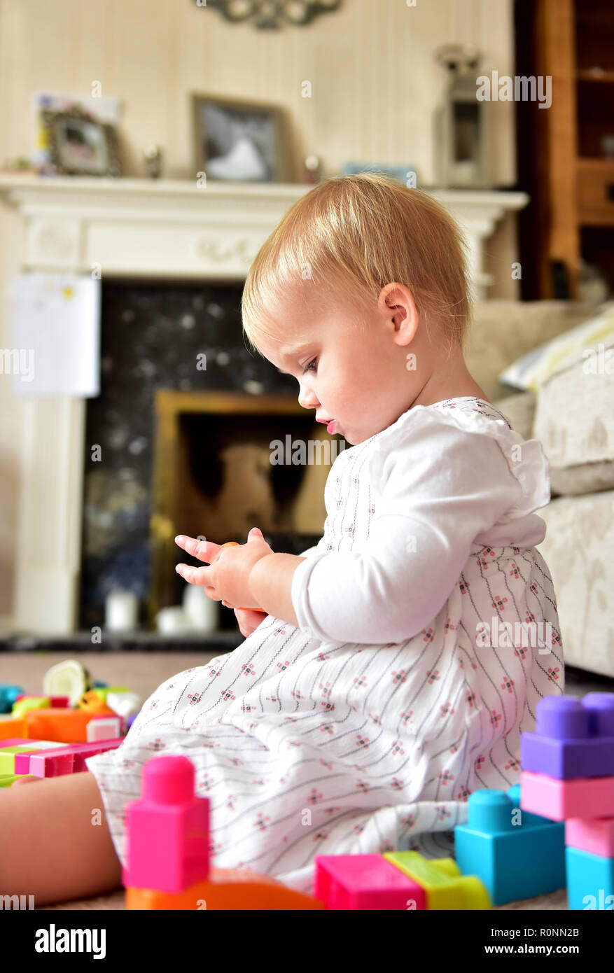 Young baby toddler girl aged two years old playing alone Photograph taken by Simon Dack Stock Photo