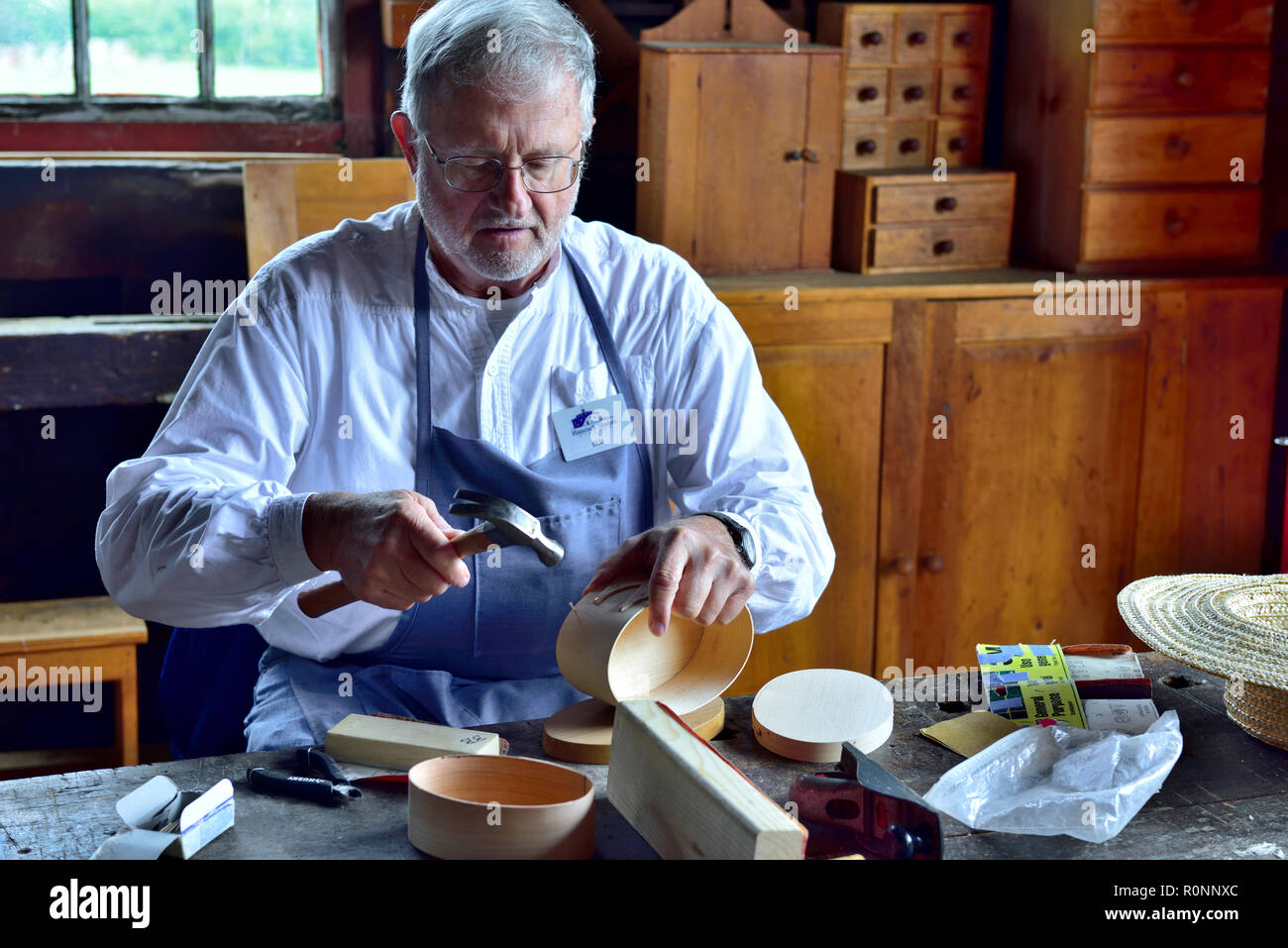 Inside Hancock Shaker Village woodworking workshop with man making a traditional oval Shaker wooden box Pittsfield MA, USA Stock Photo