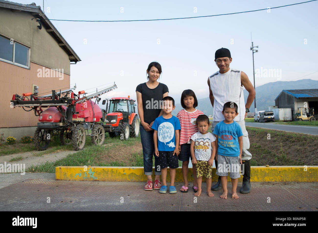 Portrait of Japanese farmer, his wife and four children standing in their yard. Stock Photo
