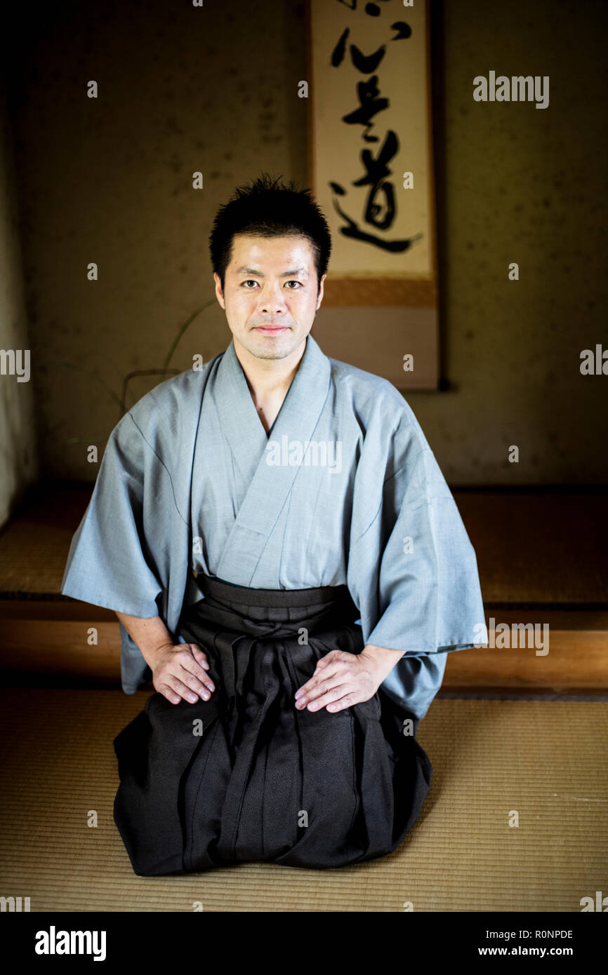 Japanese man wearing kimono sitting on floor in traditional Japanese house, looking at camera. Stock Photo