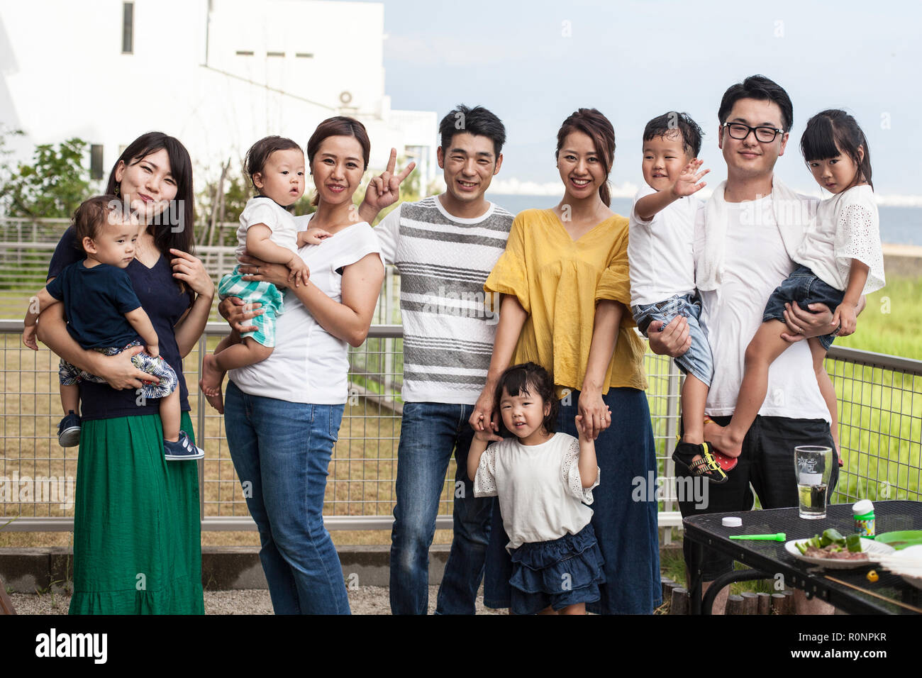 Group portrait of Japanese families with young children standing in a back garden, smiling at camera. Stock Photo