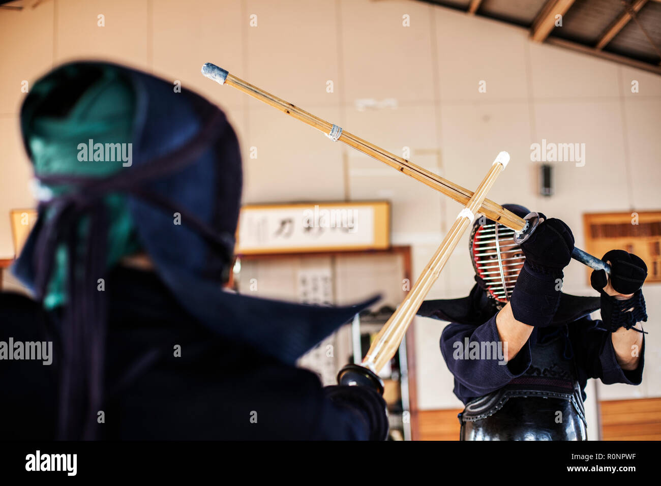 Two Japanese Kendo fighters wearing Kendo masks practicing with wood sword in gym Stock Photo