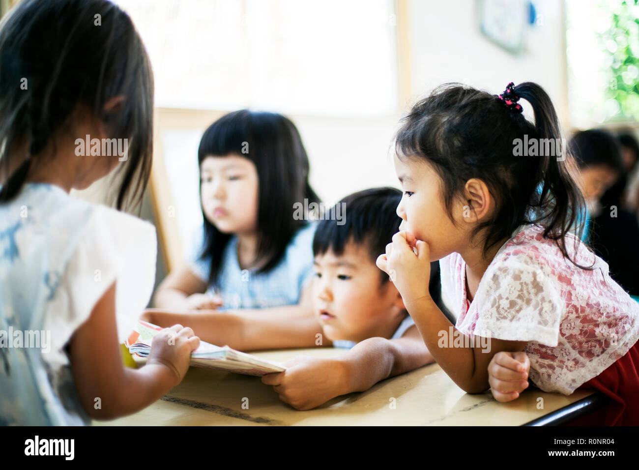 Group of children sitting at a table in a Japanese preschool. Stock Photo