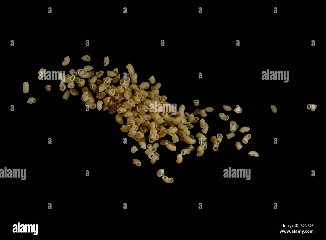 Flying pasta isolated on black background. Abstract macaroni falling. Stock Photo