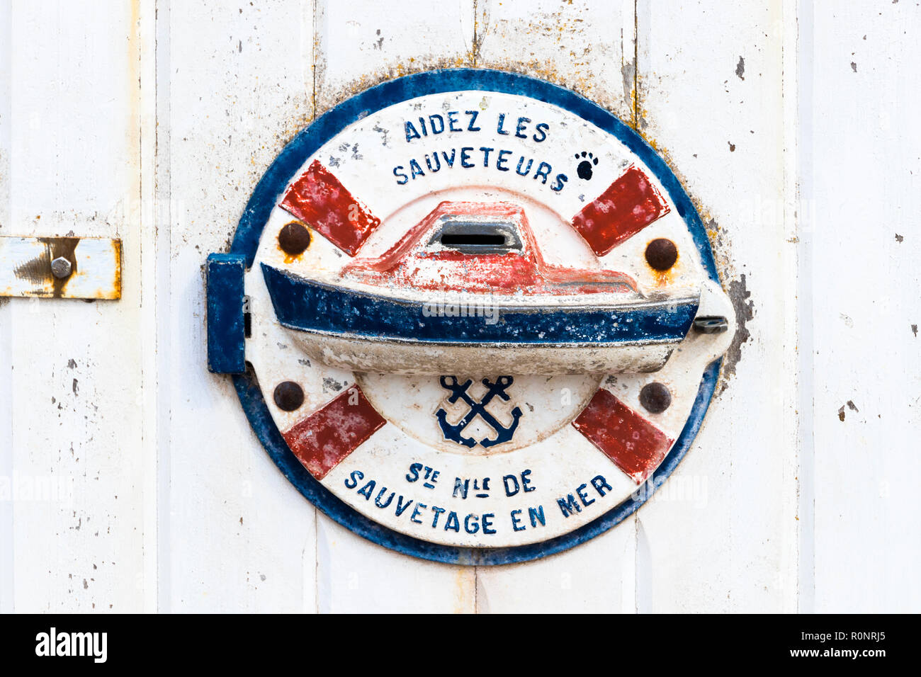 An Aidez les Sauveteurs (help the lifeguards) sign at a wooden door, from the SNSM, a French voluntary organisation that saves lives at sea around the Stock Photo