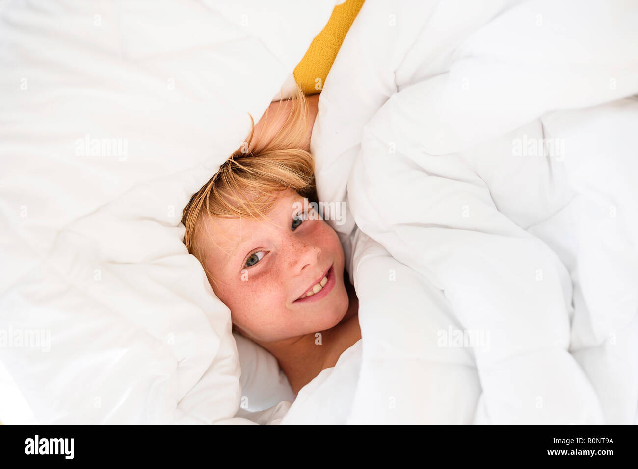 Overhead view of a smiling boy lying in bed Stock Photo