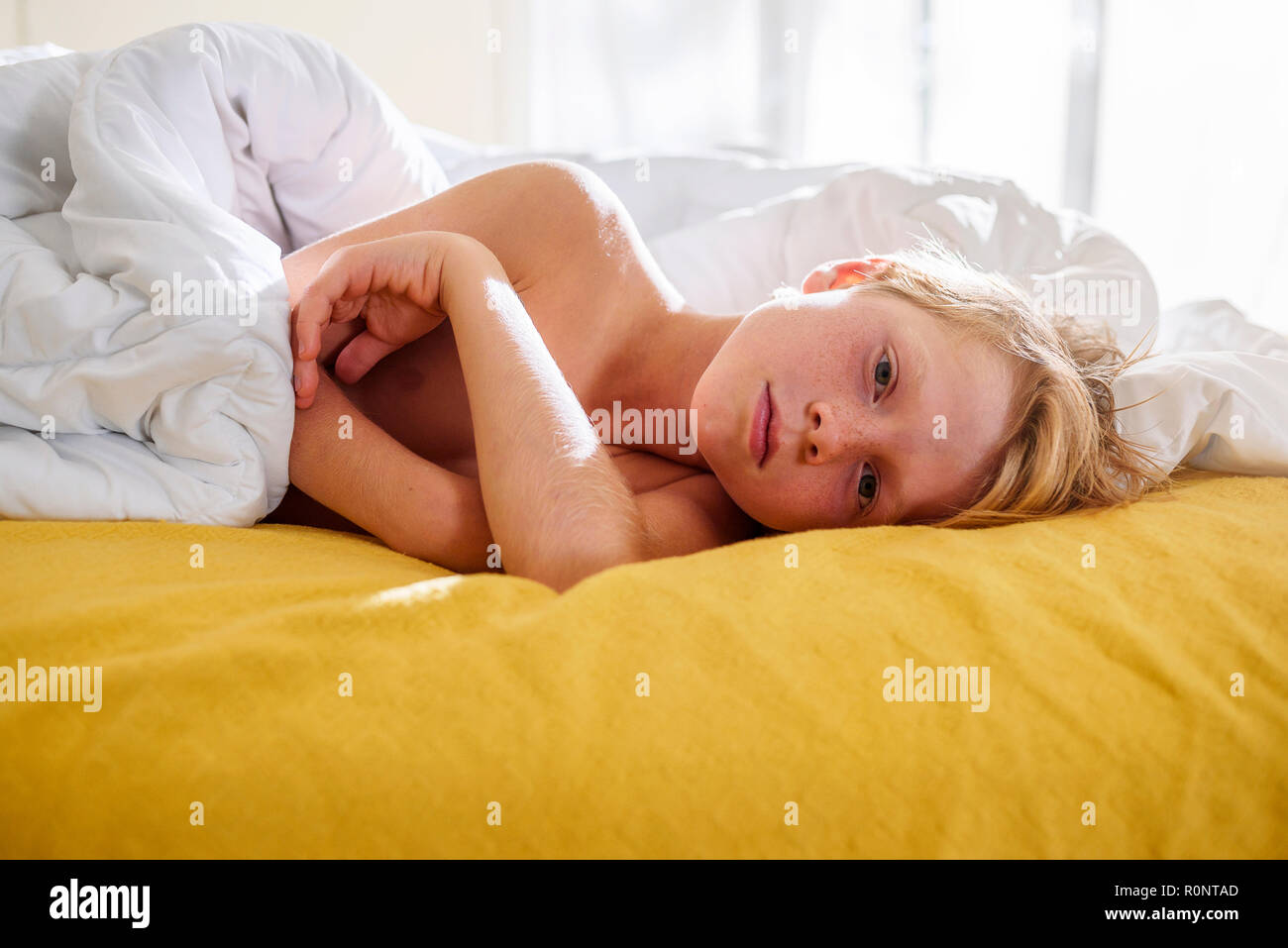 Boy lying in bed waking up Stock Photo